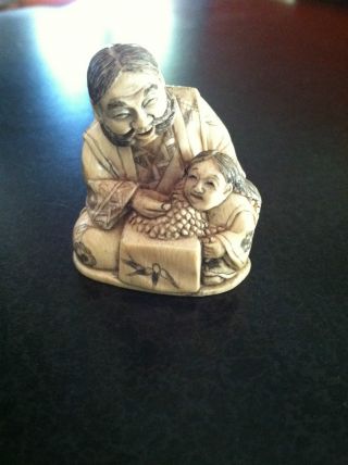 Netsuke; Antique Oxbone Carved Seated Man And Child photo