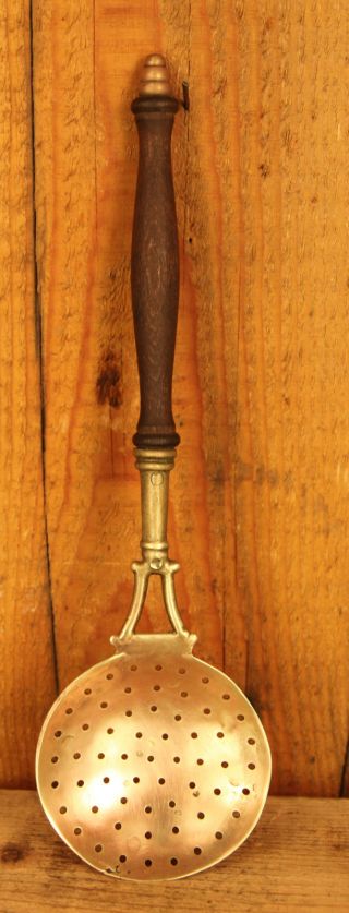 Antique Brass Strainer With A Wooden Handle photo